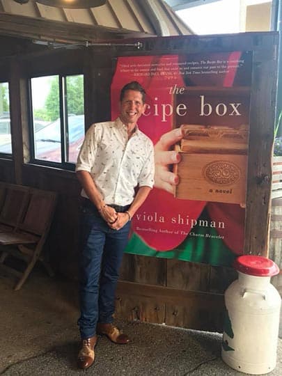 Wade Rouse/Viola Shipman in front of a poster of the cover of THE RECIPE BOX